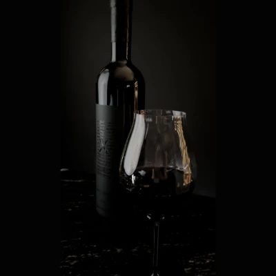 Botella y copa de vino tinto, colaboración especial entre KOLI y Casa Madero, resaltando elegancia y maridaje de alta gastronomía.
